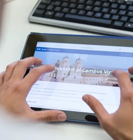 Alumno de la UCAM con una tablet entrando al Campus Virtual para visualizar sus clases online