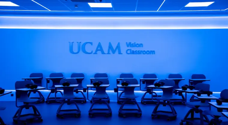 Laboratorio de VR/AR en UCAM con tecnología avanzada, incluyendo Oculus Quest, HoloLens y Apple Vision Pro, con pantalla interactiva, iluminación LED y estación de carga para dispositivos. Utilizado por para crear entornos simulados de realidad aumentada por los profesores del