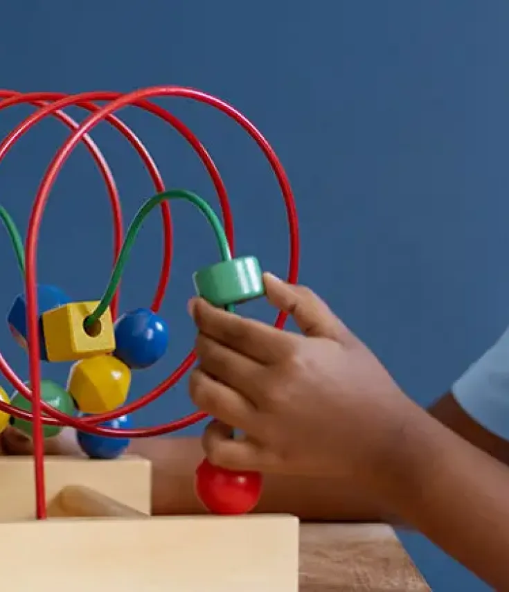 práctica de una alumna ucam con un niño interactuando con un juego de desarrollo cognitivo y motriz en clase