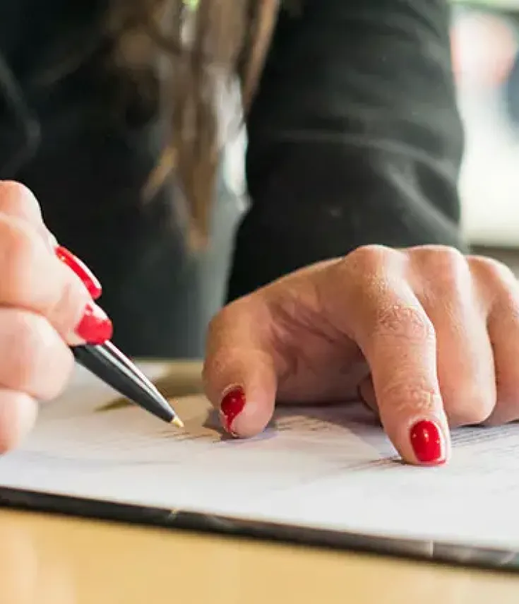 Persona firmando un contrato y revisando documentos de la sección qué aprenderás en el Máster en Asesoría Jurídico-Laboral de la UCAM