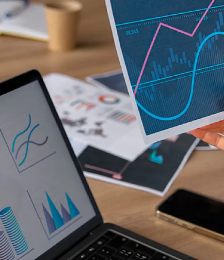 Visualización de datos empresariales y financieros con gráficos estadísticos en papel y pantalla de portátil en un entorno de análisis de Data Science.
