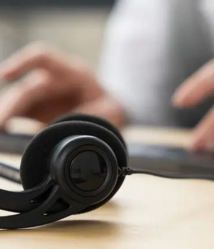 Auriculares de interpretación simultánea sobre la mesa, mientras el intérprete realiza su trabajo en el ordenador.