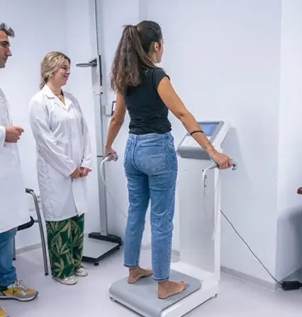 Estudiante del Grado en Nutrición Humana y Dietética de la UCAM realiza una valoración corporal con tecnología especializada, supervisada por el equipo docente, destacando la formación práctica y aplicada en entornos simulados.