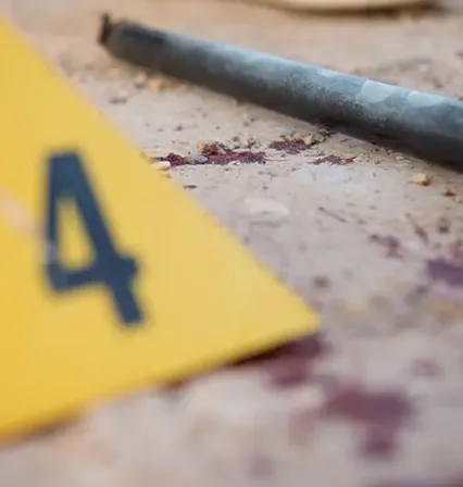 Marcador de evidencia y barra metálica en una simulación de escena del crimen del Grado en Criminología de la UCAM, simbolizando el trabajo analítico y la formación práctica en investigación forense.