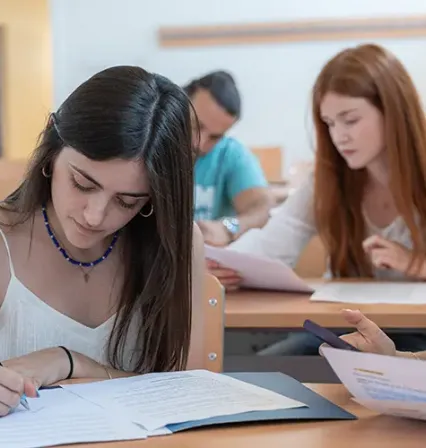 Estudiantes del Grado en Psicología de la UCAM trabajando en clase, analizando documentos y desarrollando competencias académicas en un entorno formativo participativo.