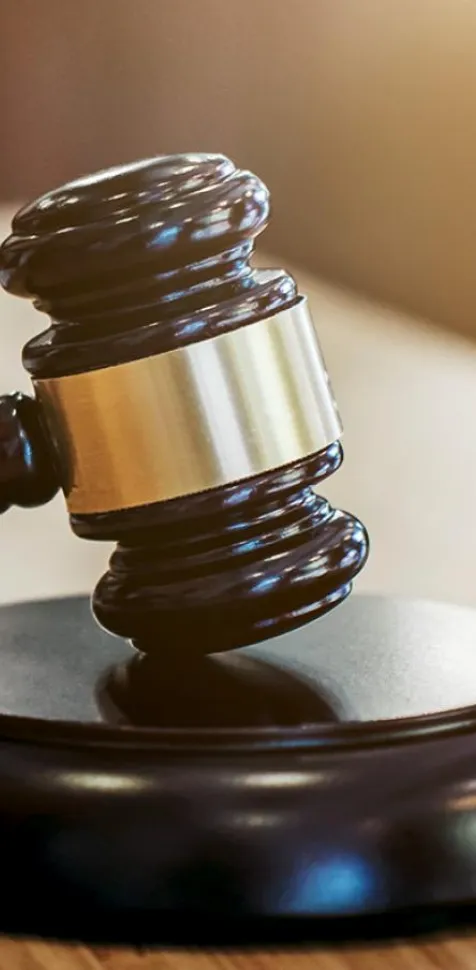 Un mazo judicial sobre una mesa y una persona firmando documentos legales, simbolizando la formación práctica, ética y profesional del Grado en Derecho de la UCAM en el Campus de Murcia.