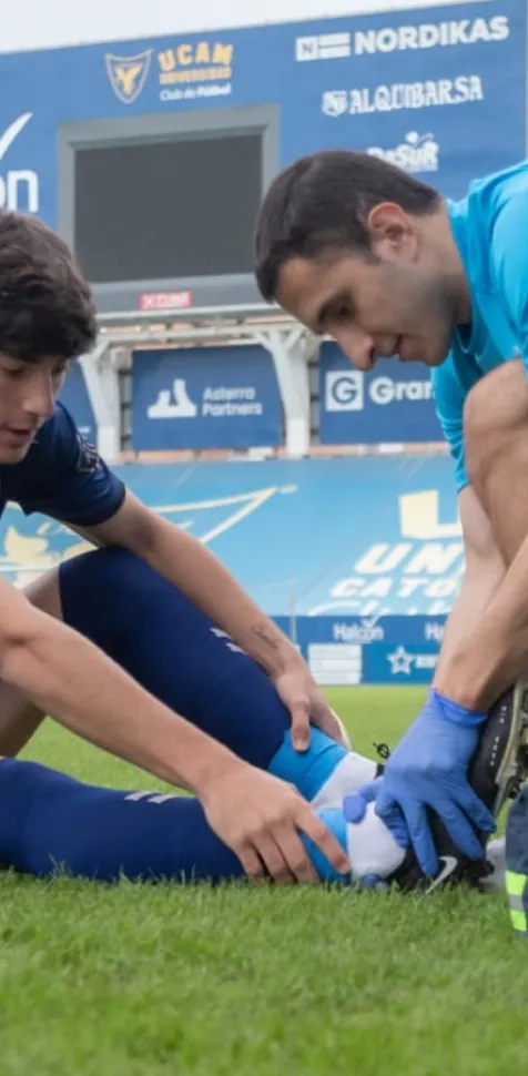 Fisioterapeuta dando un masaje a un futbolista de la UCAM