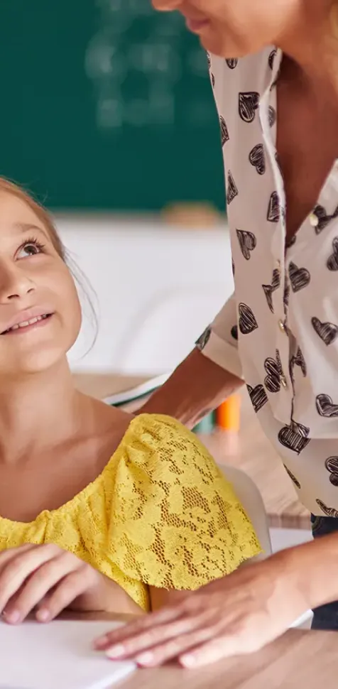 Niños de educación primaria mirando a su profesora mientras les explica nuevos conceptos en el aula.