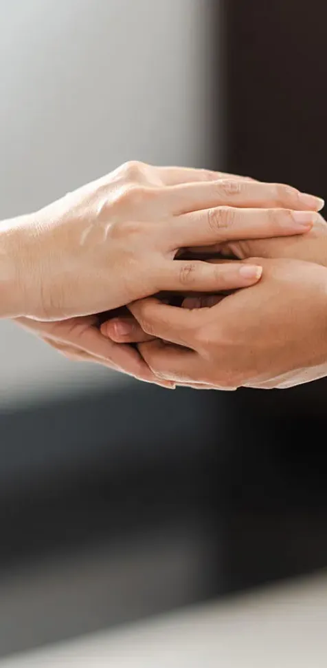 Psicólogo tomando de las manos a un paciente para apoyarlo durante su terapia