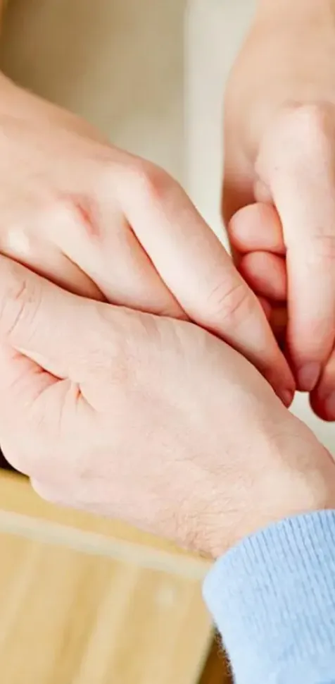 Psicólogo tomando de las manos a un paciente para apoyarlo durante su terapia.