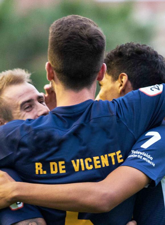 Jugadores de futbol abranzándose