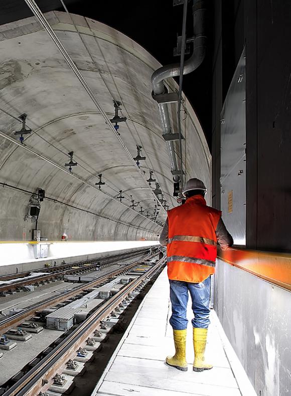Un hombre en un túnel con cableado y vías de un tres 