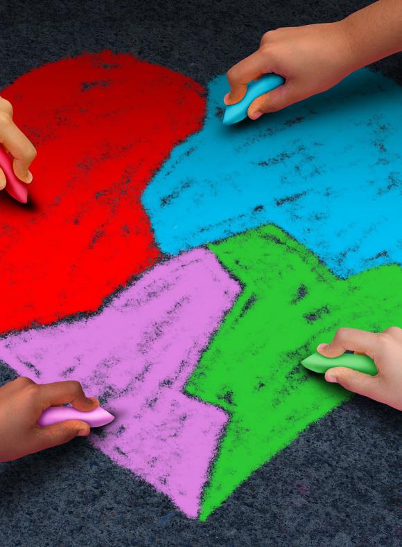 manos de unos niños dibujando un corazón de tizas de colores en el suelo