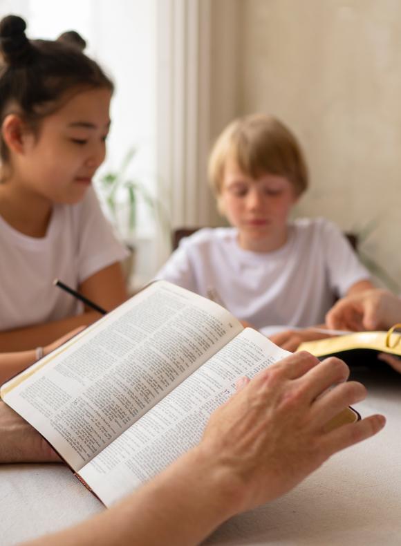 Unos niños y las manos de un adulto leyendo la 