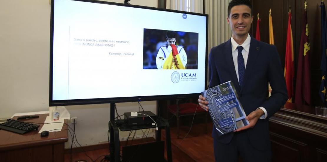 El campeón olímpico y mundial de taekwondo, Joel González, posa con su tesis tras doctorarse por la UCAM.